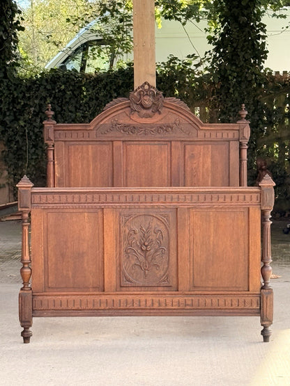 Henri II carved oak footboard in front of matching headboard