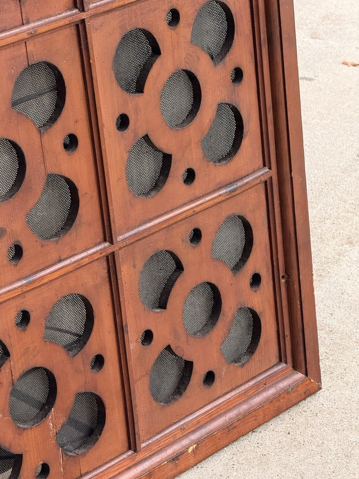 Close-up of pierced roundels and wire mesh, pine ventilation panel