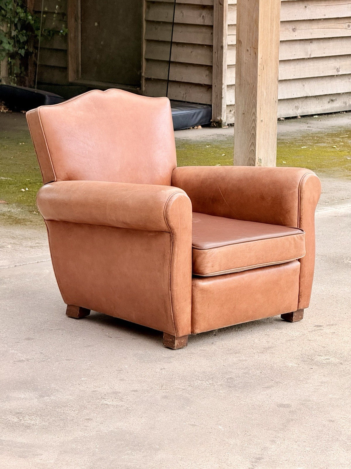 French Art Deco moustache leather club armchair, three-quarter view outdoors