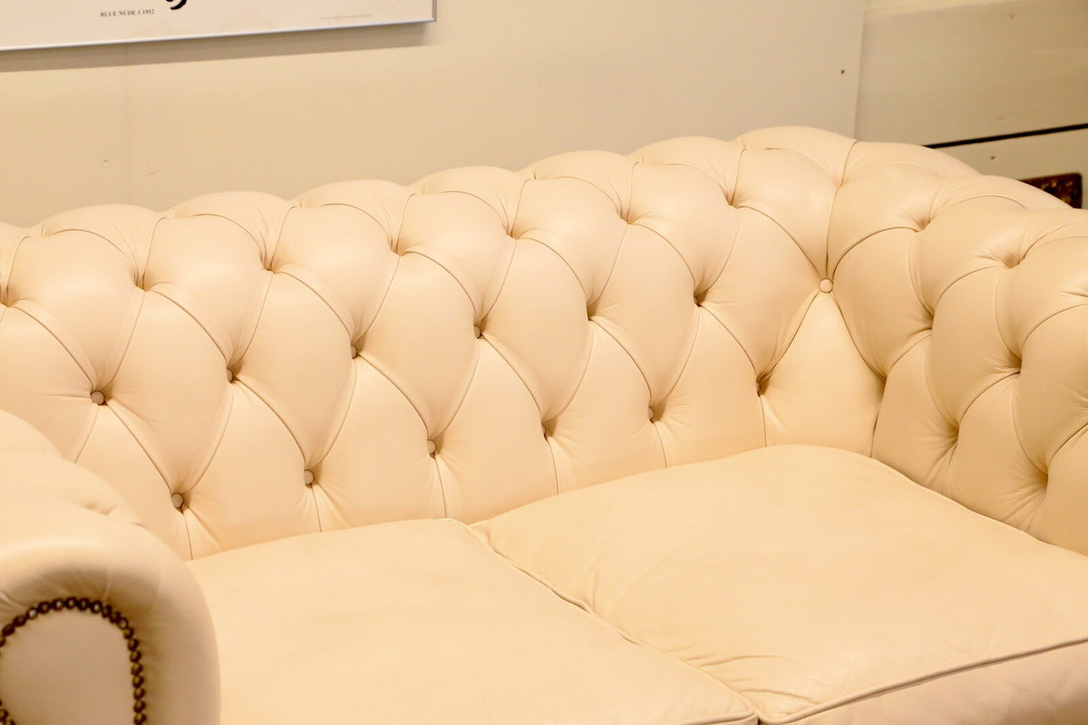 Close-up of deep-buttoned back and seat cushions, cream Chesterfield sofa