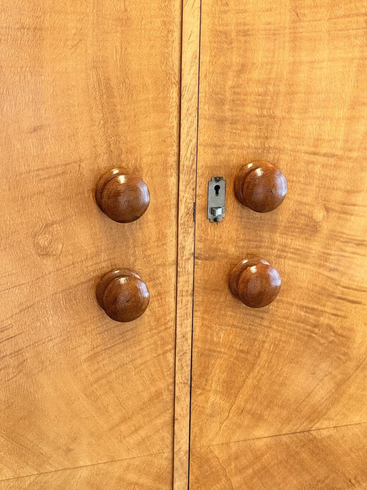 Close-up of round wooden knobs and lock on the bird's eye maple doors