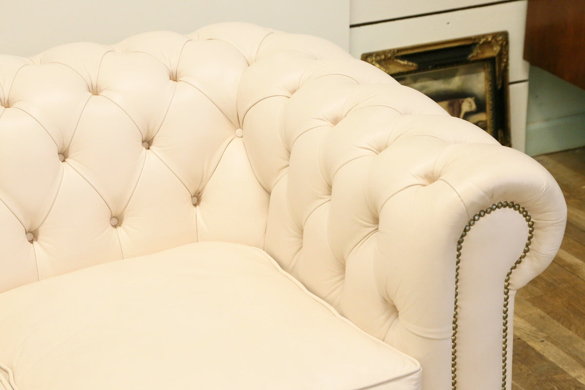 Close-up of buttoned back and rolled arm, cream leather sofa