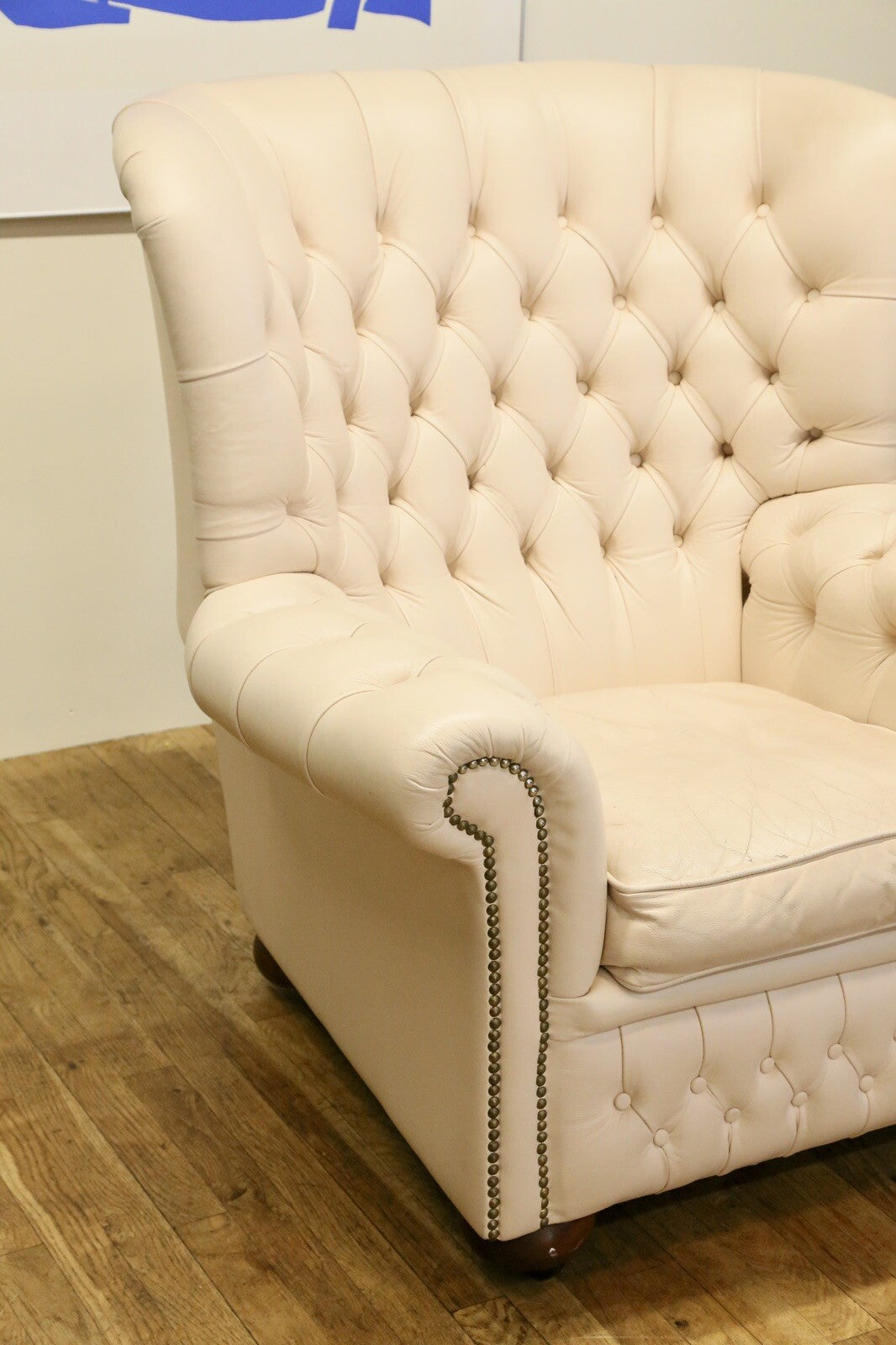 Cream leather Chesterfield wing armchair, angled view of seat and arm