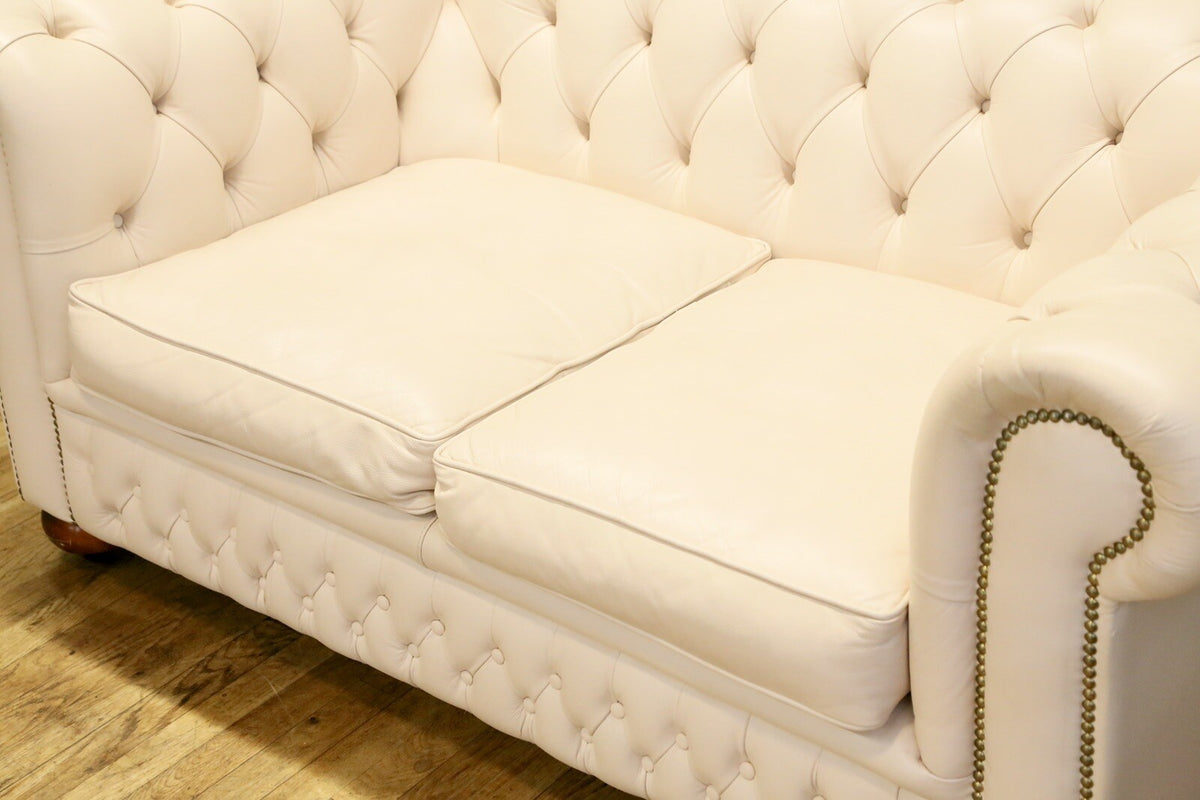 Cream leather Chesterfield sofa seat cushions and stud-trimmed arm