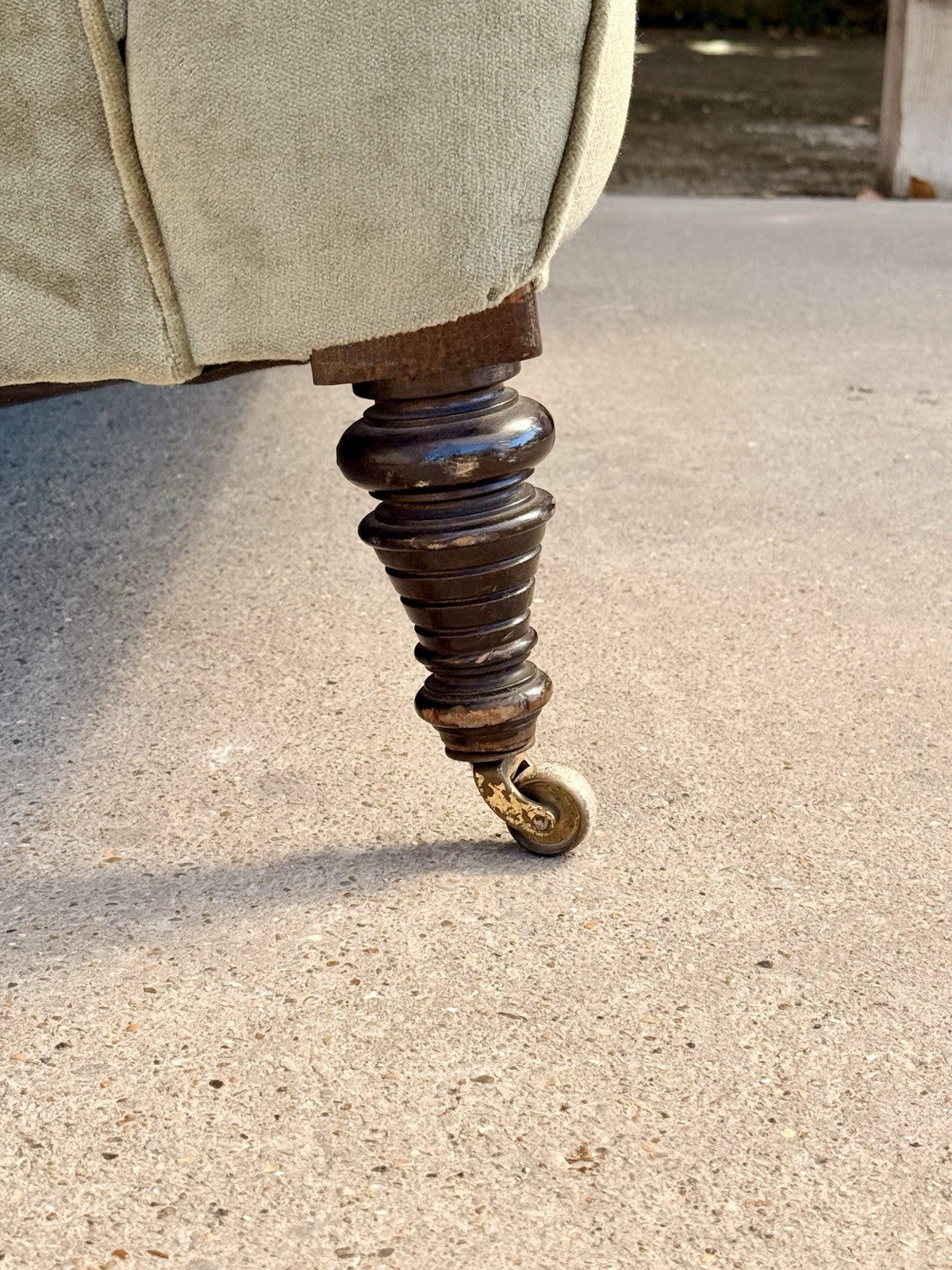 Close-up of turned wooden leg on brass castor, 19th-century sofa
