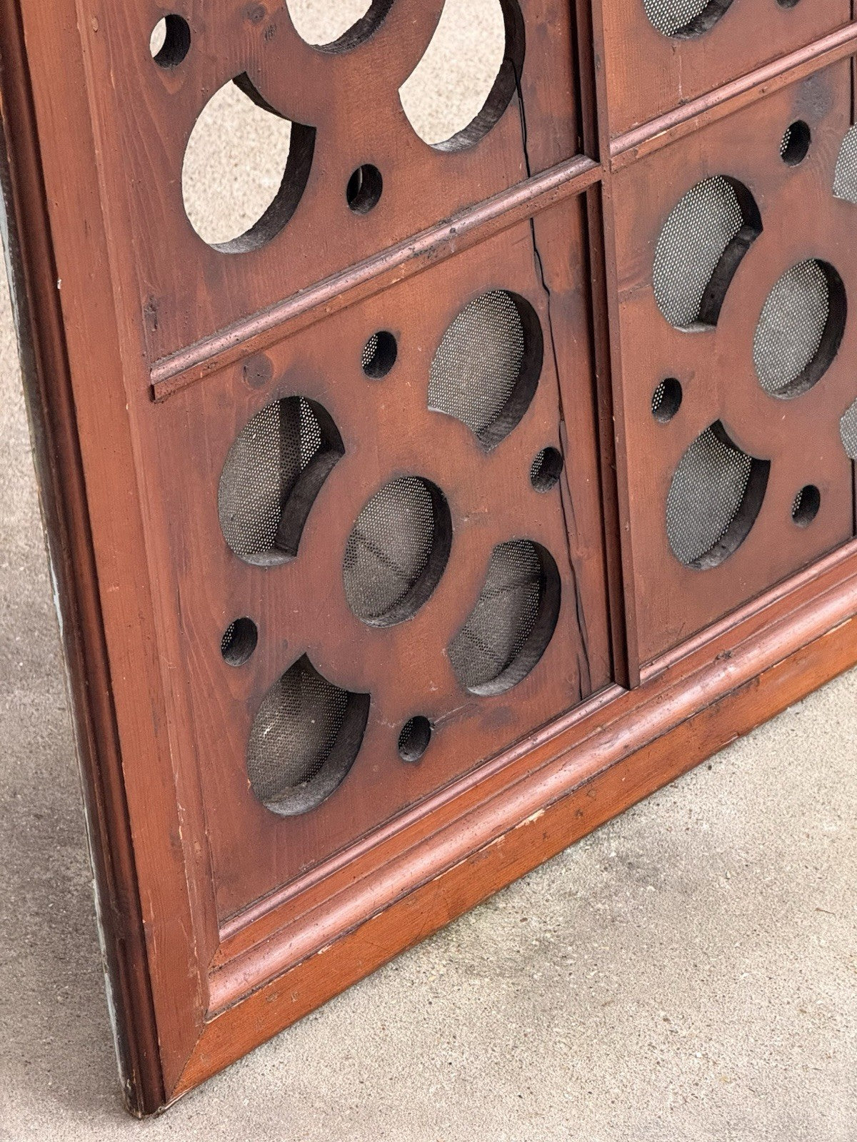 Close-up of quatrefoil cutouts with mesh partly missing