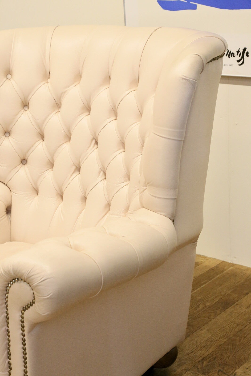Close-up of buttoned wing and arm, cream leather Chesterfield