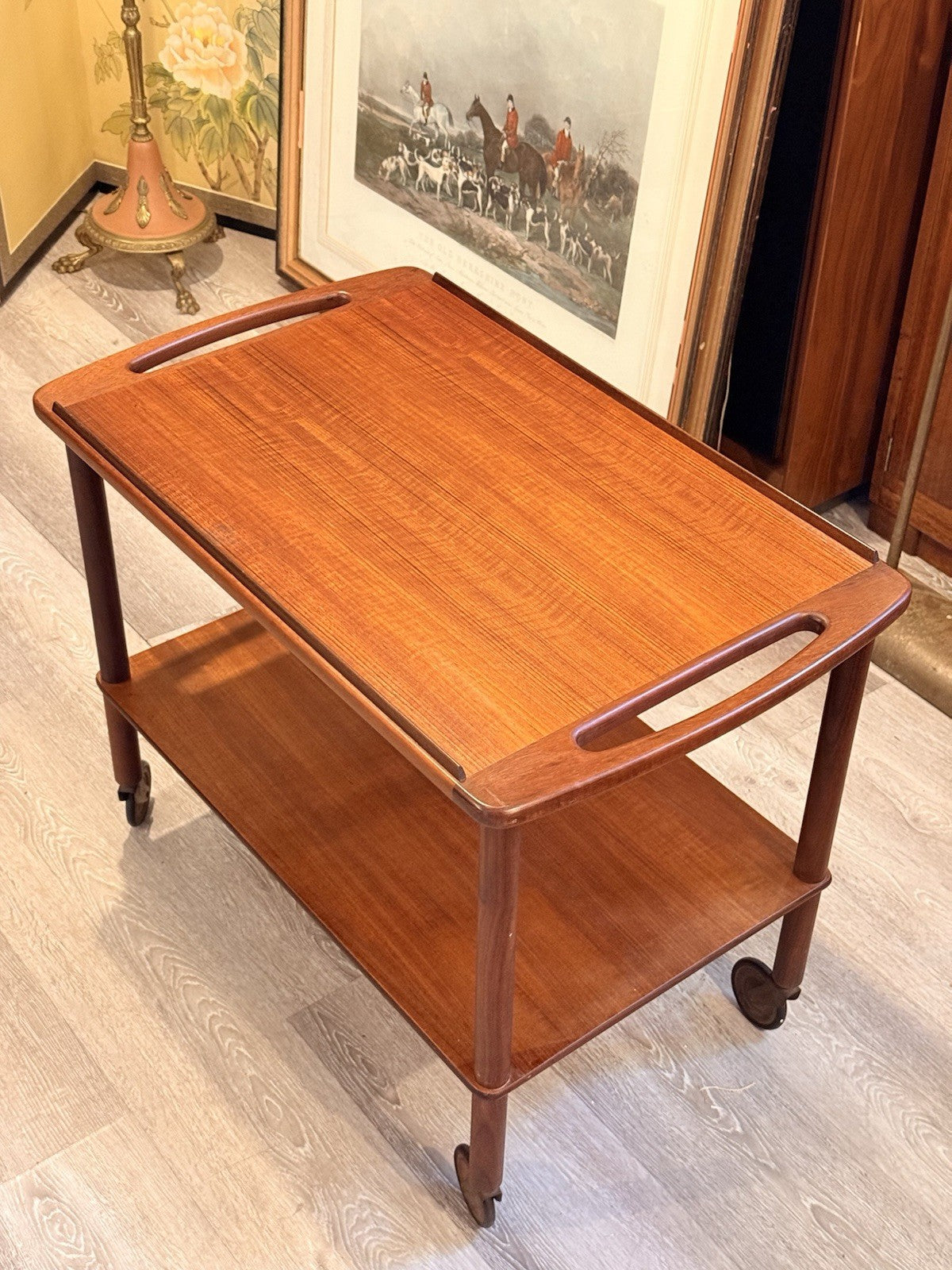 Bowa teak drinks trolley, three-quarter view in front of a hunting print