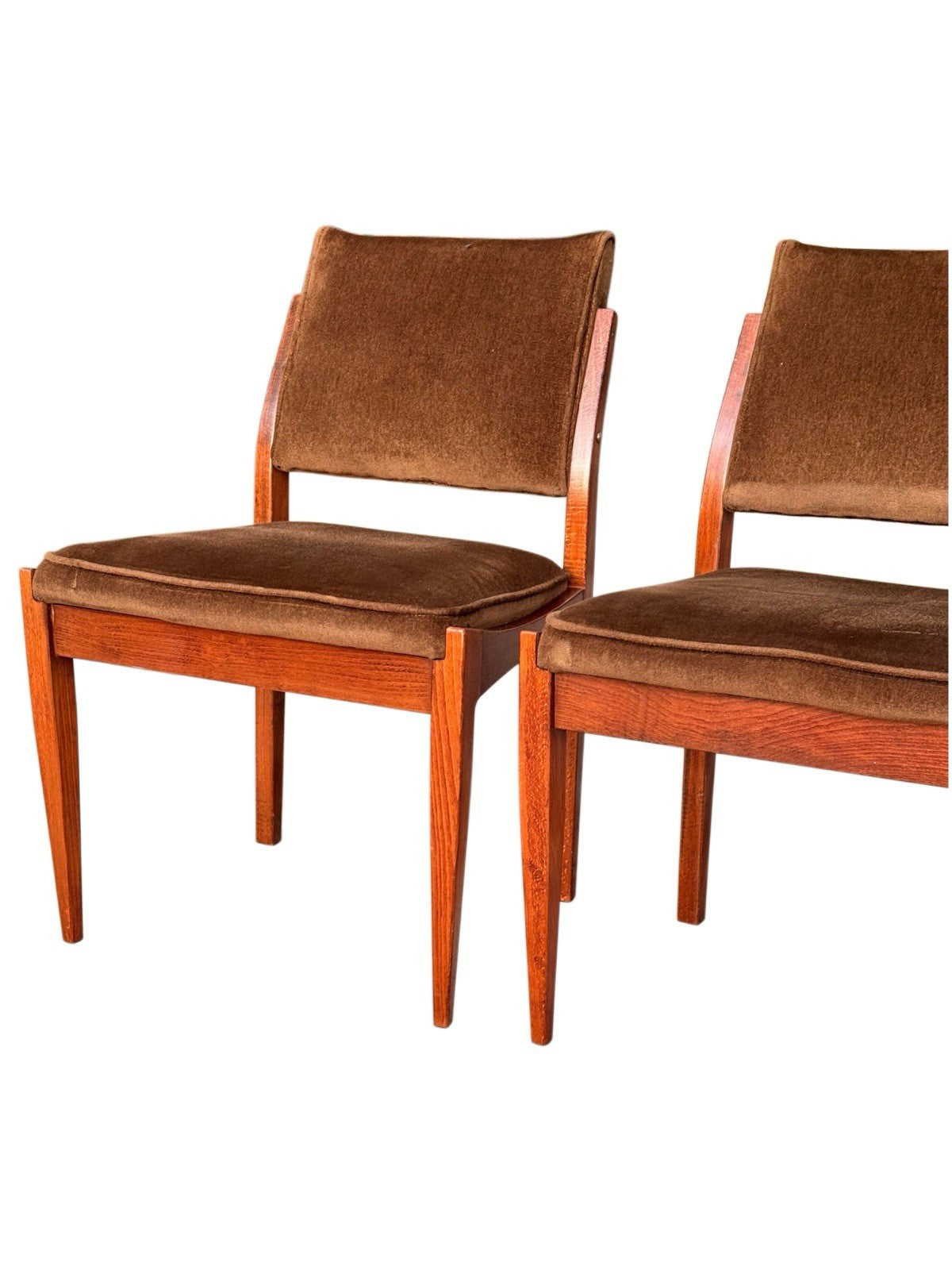 Close-up of two mid-century dining chairs with brown upholstered seats