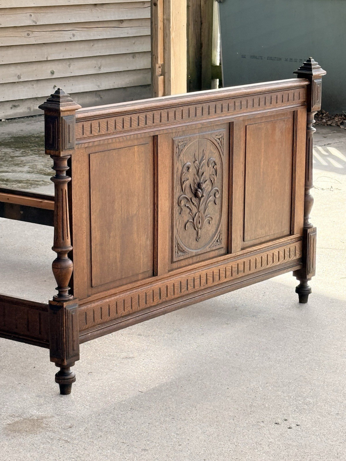Carved oak footboard with central floral panel and turned posts, French bed