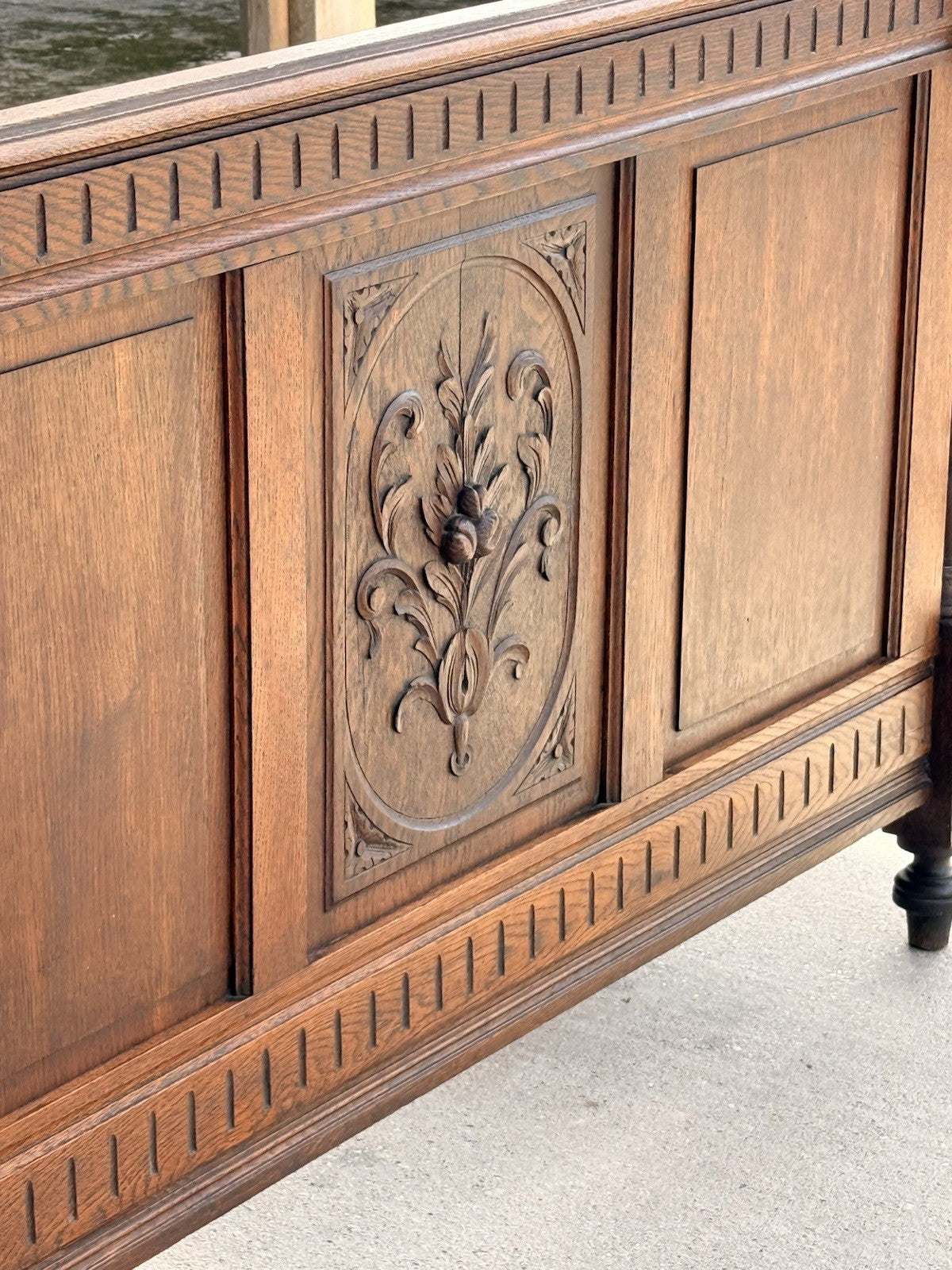 Close-up of carved floral panel and fluted frieze on the oak footboard