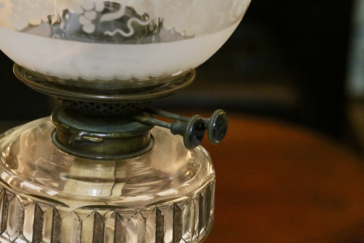 Close-up of brass burner and wick winder under the etched shade