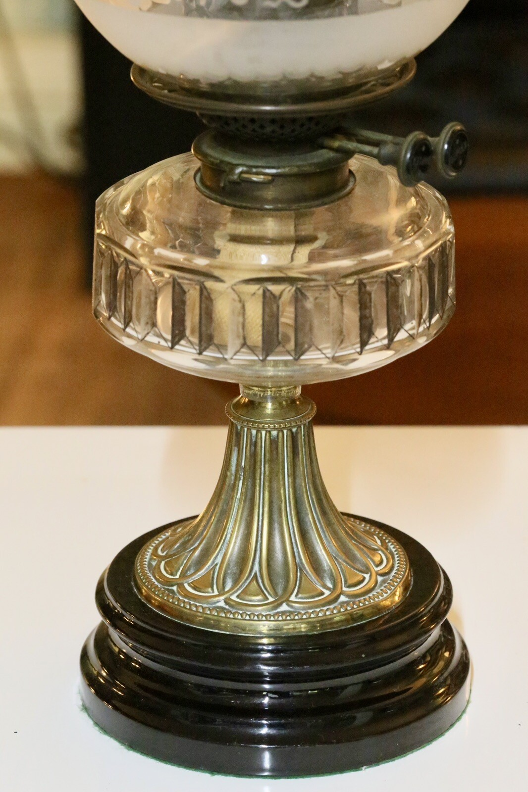 Close-up of crystal reservoir on fluted brass column and black base