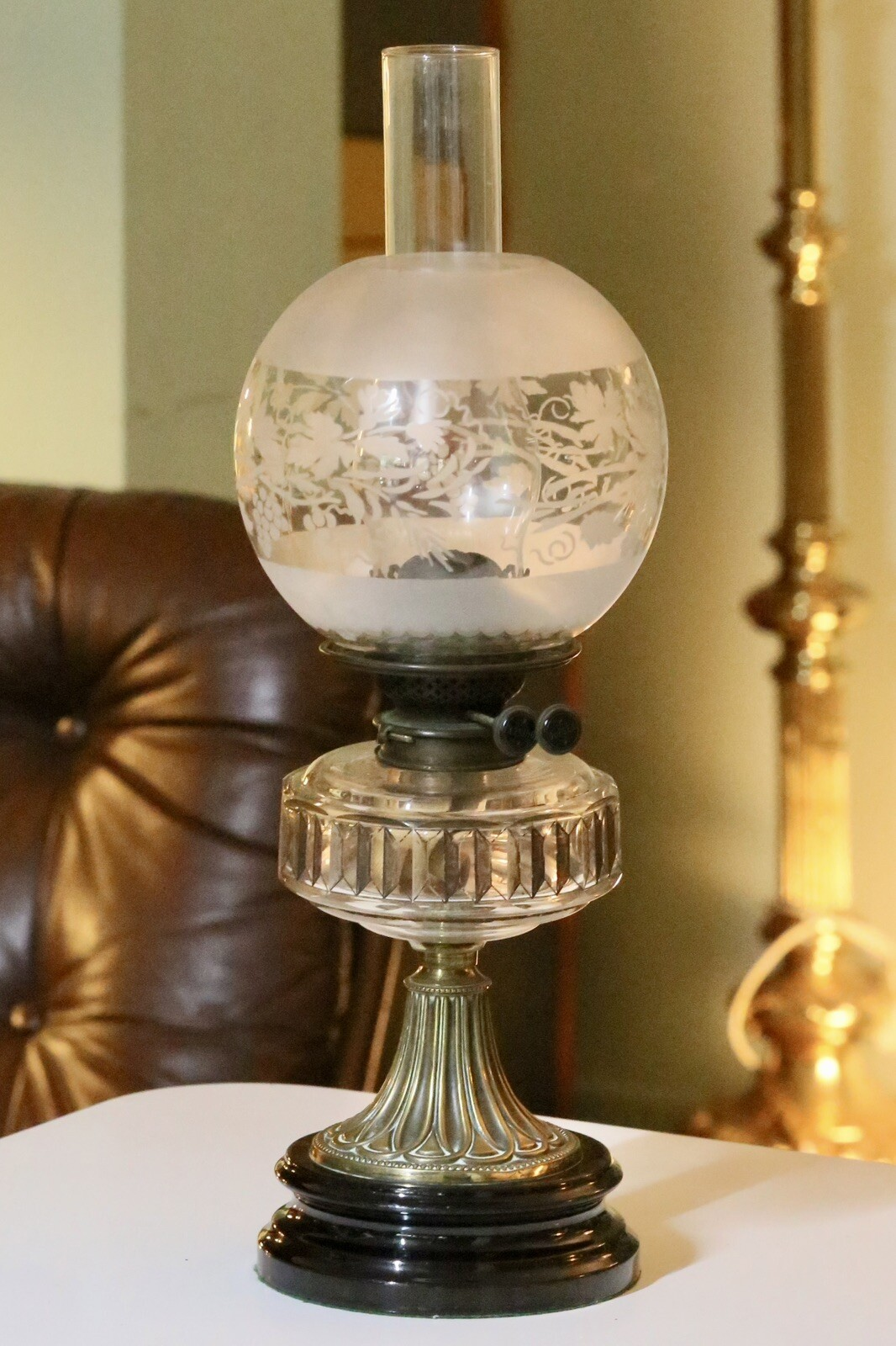 Victorian Art Nouveau brass oil lamp with crystal glass reservoir, front view with globe shade