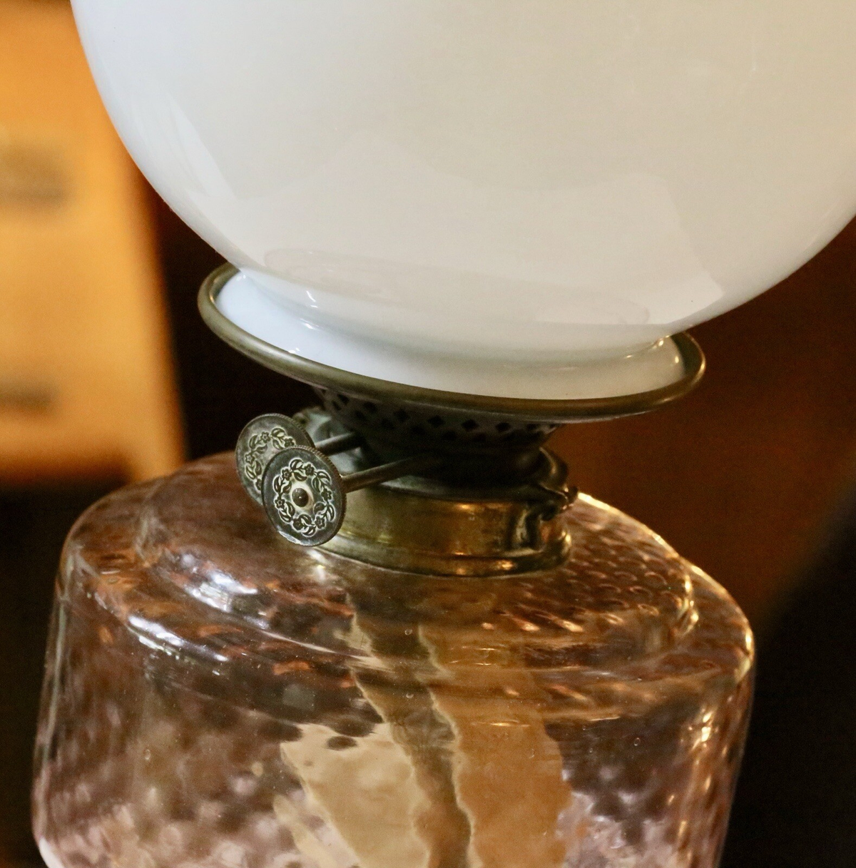 Close-up of brass burner and wick winder under the opaline shade