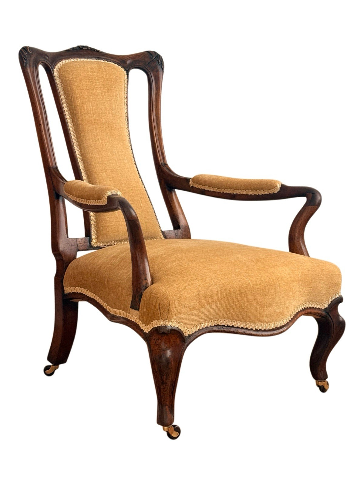 Victorian carved rosewood lounge armchair on cabriole legs and casters with golden-yellow upholstery