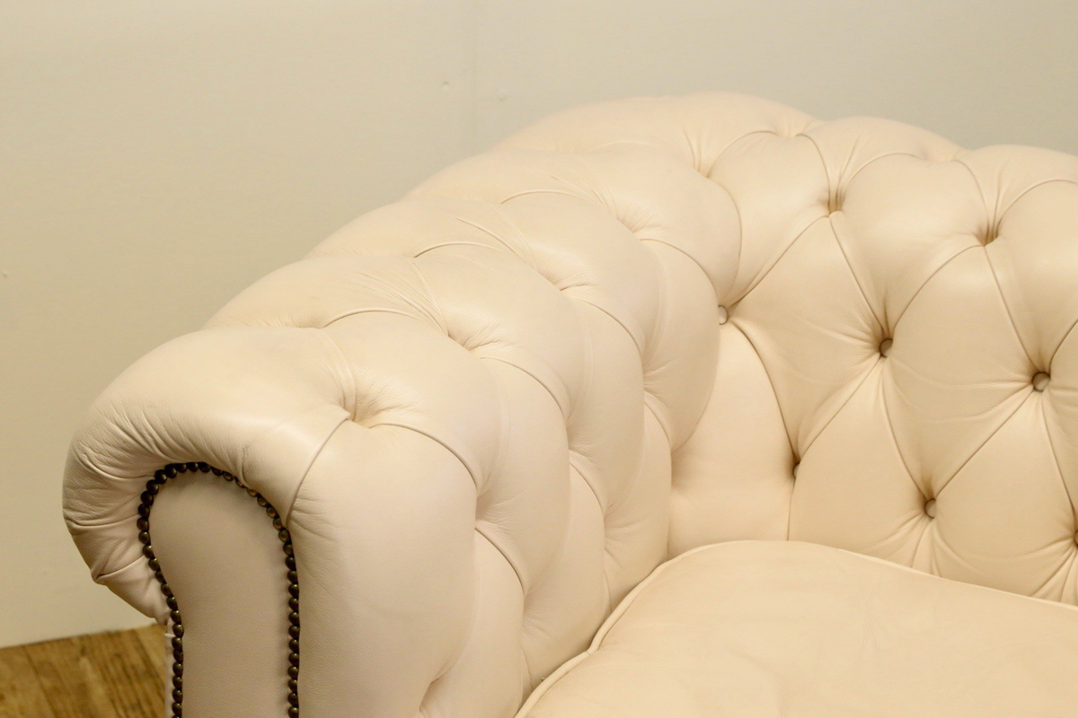 Close-up of deep buttoned back and rolled arm with brass studs